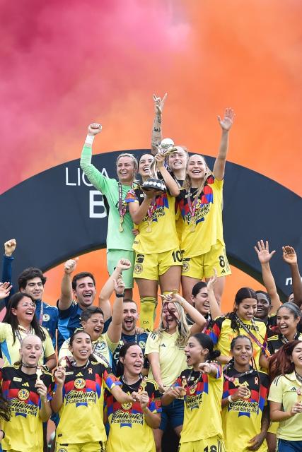 America's forward #10 Scarlett Camberos (C) lifts the trophy with her teammates after winning the Liga MX Femenil women's Clausura final second-leg football match between America and Monterrey at the Ciudad de los Deportes stadium in Mexico City on May 17, 2026. (Photo by Rodrigo Oropeza / AFP)