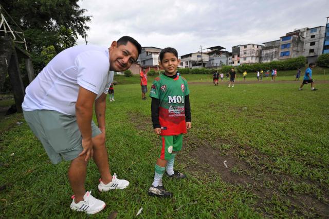 Dilmer Hidalgo and his son Julian pose for a photo during a training session at the IG 10 Moises Caicedo football school in the Mujer Trabajadora neighborhood in Santo Domingo, Ecuador, on May 8, 2026. Amid the tightly packed houses of a working-class Ecuadorian neighborhood, national team football player Moises Caicedo lifted his first trophies. They were made of gold-colored plastic, lent by a neighbor to add excitement to the impromptu game played by a group of children from which one of the world's most highly regarded midfielders emerged. Caicedo, now a Chelsea player, will compete in his second World Cup with Ecuador at just 24 years old. (Photo by Rodrigo BUENDIA / AFP)