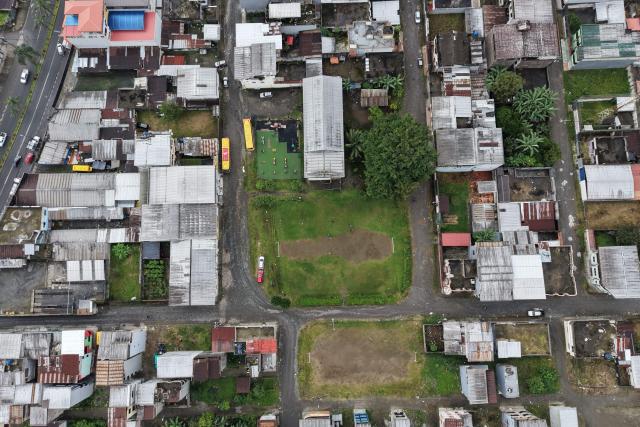This aerial view shows the pitch during a training session at the IG 10 Moises Caicedo football school in downtown Santo Domingo, Ecuador, on May 8, 2026. Amid the tightly packed houses of a working-class Ecuadorian neighborhood, national team football player Moises Caicedo lifted his first trophies. They were made of gold-colored plastic, lent by a neighbor to add excitement to the impromptu game played by a group of children from which one of the world's most highly regarded midfielders emerged. Caicedo, now a Chelsea player, will compete in his second World Cup with Ecuador at just 24 years old. (Photo by Rodrigo BUENDIA / AFP)