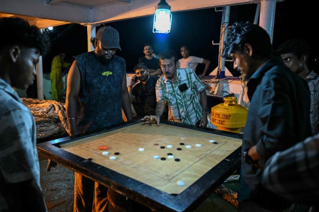 This photograph taken on March 30, 2026 shows passengers playing carrom game on the MV Kalighat vessel plying across the waters of India's Andaman and Nicobar Islands. Running from the archipelago's capital Sri Vijayapuram in the north to the southern tip of Campbell Bay, the ferry serves as both a passenger and cargo ship. (Photo by R. Satish BABU / AFP) / To go with 'India-Andaman Nicobar-Economy-Shipping-Tourism' by Bhuvan BAGGA