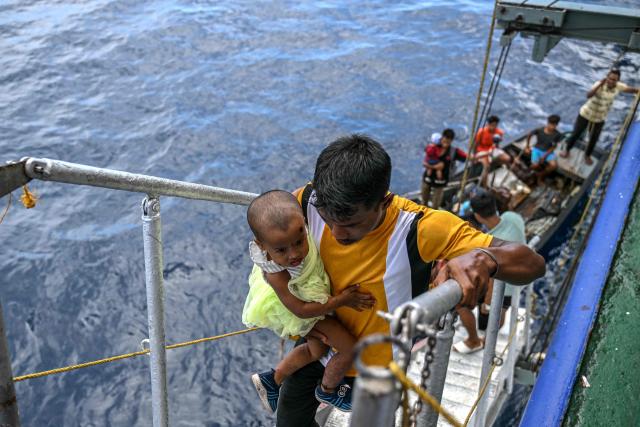 This photograph taken on March 30, 2026 shows passengers boarding the MV Kalighat vessel near Chowra in the waters of India's Andaman and Nicobar Islands. Running from the archipelago's capital Sri Vijayapuram in the north to the southern tip of Campbell Bay, the ferry serves as both a passenger and cargo ship. (Photo by R. Satish BABU / AFP) / To go with 'India-Andaman Nicobar-Economy-Shipping-Tourism' by Bhuvan BAGGA