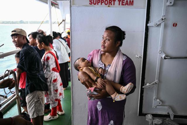 This photograph taken on March 30, 2026 shows a woman along with her child waiting to disembark the MV Kalighat vessel near Chowra in the waters of India's Andaman and Nicobar Islands. Running from the archipelago's capital Sri Vijayapuram in the north to the southern tip of Campbell Bay, the ferry serves as both a passenger and cargo ship. (Photo by R. Satish BABU / AFP) / To go with 'India-Andaman Nicobar-Economy-Shipping-Tourism' by Bhuvan BAGGA