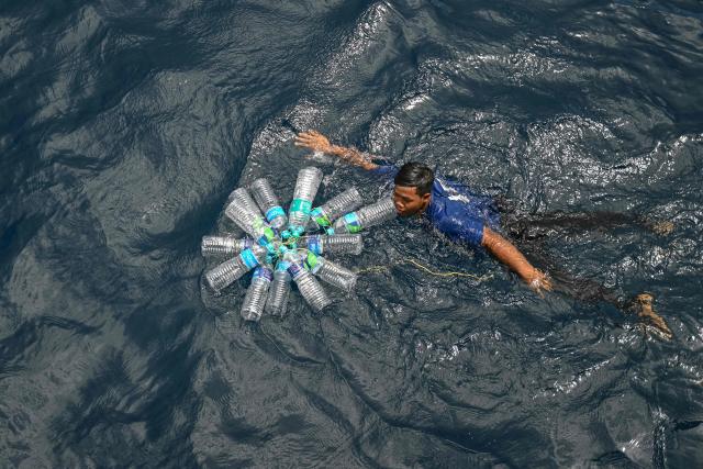 This photograph taken on March 30, 2026 shows a passenger retrieving his plastic bottles after they fell down while travelling on the MV Kalighat vessel near Chowra in the waters of India's Andaman and Nicobar Islands. Running from the archipelago's capital Sri Vijayapuram in the north to the southern tip of Campbell Bay, the ferry serves as both a passenger and cargo ship. (Photo by R. Satish BABU / AFP) / To go with 'India-Andaman Nicobar-Economy-Shipping-Tourism' by Bhuvan BAGGA