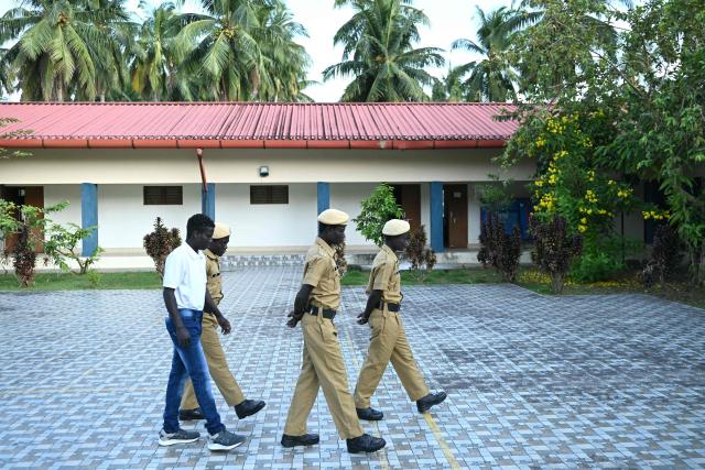 This photograph taken on March 22, 2026 shows members of the Onge tribal community who joined as police homeguards, walking inside the Hut Bay police station on Little Andaman island in India's Andaman and Nicobar Islands. Outsiders call the Indian Ocean island Little Andaman and its long-isolated guardians the Onge, but those preserving an age-old way of life now under threat have their own names. A $9 billion development plan across India's wider Andaman and Nicobar Islands will affect communities throughout the scattered archipelago. Authorities, treading a delicate line in managing contact, began last year recruiting more than 500 young men from communities across the archipelago as police "homeguards" to help manage relations with outsiders. (Photo by R. Satish BABU / AFP)
