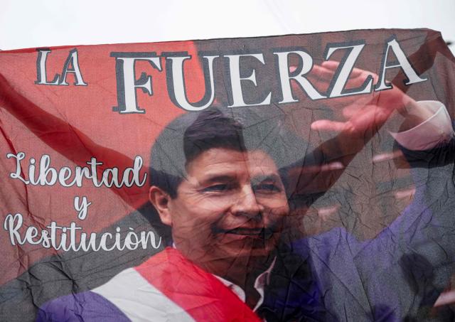 A supporter of Peru's presidential candidate Roberto Sanchez, of the Juntos por el Peru party, holds a flag with the image of convict former President Pedro Castillo during a campaign rally in Lima on May 17, 2026. Left-wing candidate Roberto Sanchez has qualified for the runoff of Peru's presidential election and will face right-wing candidate Keiko Fujimori in June 7. (Photo by Ernesto BENAVIDES / AFP)