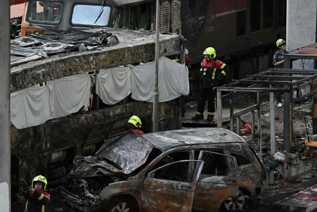 (FILES) Firefighters and rescue workers surround the aftermath of a train collision with a bus underneath Makkasan Airport Rail station in Bangkok on May 16, 2026. The driver of a train that collided with a bus in Thailand's capital, killing eight people, has tested positive for drugs and was charged with reckless driving, police said on May 18, 2026. (Photo by Lillian SUWANRUMPHA / AFP)
