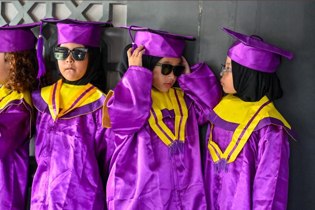 Kindergarteners in gowns look on as they wait to have their graduation photographs taken at the Aceh Tsunami Museum on International Museum Day in Banda Aceh on May 18, 2026. (Photo by CHAIDEER MAHYUDDIN / AFP)