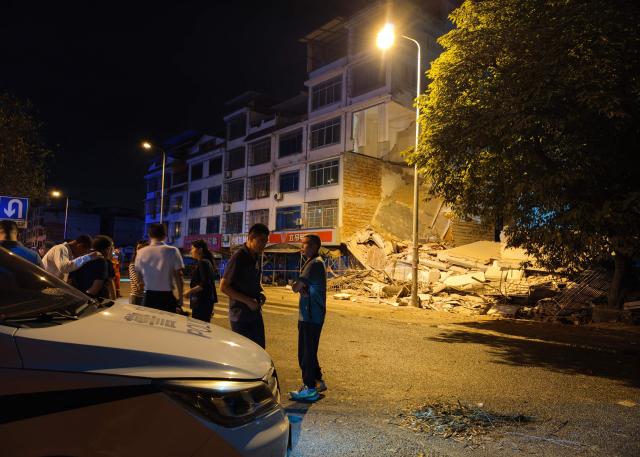 Poeple stand outside a collapsed building after an earthquake in Liuzhou, China's southern Guangxi region on May 18, 2026. A 5.2-magnitude earthquake struck south China's Guangxi region on May 18, killing two people and causing 13 buildings to collapse, state media reported. (Photo by CNS / AFP) / China OUT