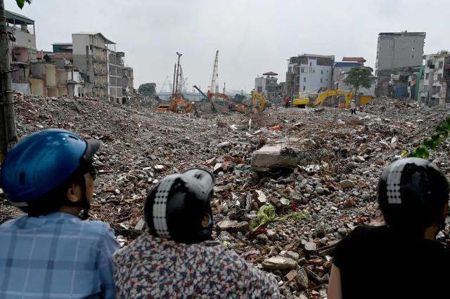Onlookers view a field of rubble from residential buildings at a demolition site to make way for an expanded road network in Hanoi on May 18, 2026. (Photo by Nhac NGUYEN / AFP)