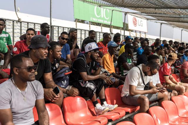 Supporters watch from the stands during the Praia Cup final football match between Desportivo da Praia and Sporting Clube da Praia at the Estadio da Varzea in Praia, on April 4, 2026. Both teams played the final for a chance to qualify for the Cape Verdean Cup, a knockout tournament that brings together the champions of each island. 
This archipelago of 10 islands is the smallest African nation ever to qualify for a World Cup with a population of just 550,000. 
The national team, known as the Blue Sharks, will compete in Group H against Spain, Saudi Arabia, and Uruguay. 
Their World Cup qualification has inspired many players in the local leagues, who now dream of joining the national team and representing their country. (Photo by PATRICK MEINHARDT / AFP)