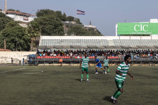 A flag of Cape Verde is seen flying off a mast during the Praia Cup final football match between Desportivo da Praia and Sporting Clube da Praia at the Estadio da Varzea in Praia, on April 4, 2026. Both teams played the final for a chance to qualify for the Cape Verdean Cup, a knockout tournament that brings together the champions of each island. 
This archipelago of 10 islands is the smallest African nation ever to qualify for a World Cup with a population of just 550,000. 
The national team, known as the Blue Sharks, will compete in Group H against Spain, Saudi Arabia, and Uruguay. 
Their World Cup qualification has inspired many players in the local leagues, who now dream of joining the national team and representing their country. (Photo by PATRICK MEINHARDT / AFP)