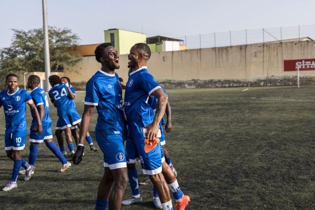 Desportivo da Praia players celebrate after winning the Praia Cup final football match between Desportivo da Praia and Sporting Clube da Praia at the Estadio da Varzea in Praia, on April 4, 2026. Both teams played the final for a chance to qualify for the Cape Verdean Cup, a knockout tournament that brings together the champions of each island. 
This archipelago of 10 islands is the smallest African nation ever to qualify for a World Cup with a population of just 550,000. 
The national team, known as the Blue Sharks, will compete in Group H against Spain, Saudi Arabia, and Uruguay. 
Their World Cup qualification has inspired many players in the local leagues, who now dream of joining the national team and representing their country. (Photo by PATRICK MEINHARDT / AFP)