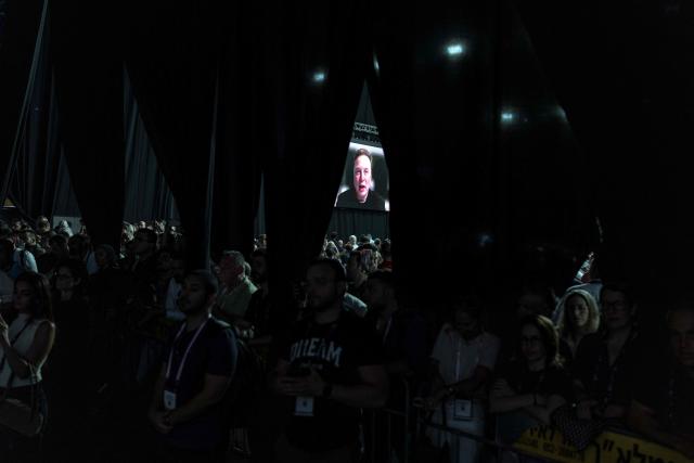 Tesla and SpaceX CEO Elon Musk is seen on a large screen during a long distance Q&A session at the Smart Mobility Summit 2026, in Tel Aviv on May 18, 2026. (Photo by ilia YEFIMOVICH / AFP)