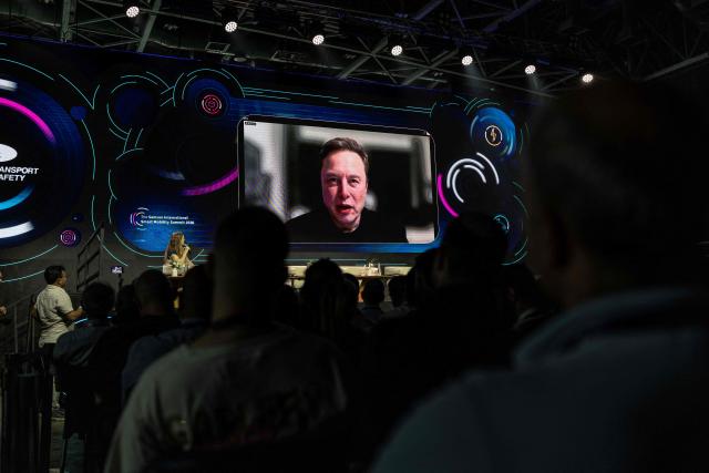 Tesla and SpaceX CEO Elon Musk is seen on a large screen during a long distance Q&A session at the Smart Mobility Summit 2026, in Tel Aviv on May 18, 2026. (Photo by ilia YEFIMOVICH / AFP)