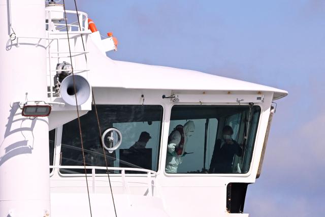 Crew members wearing protective suits and face masks are seen in the bridge of the Dutch Hantavirus-hit cruise ship MV Hondius upon its arrival at the port of Rotterdam on May 18, 2026. Cruise ship MV Hondius arrived at the port of Rotterdam and the ship's crew members will undergo a medical screening. (Photo by JOHN THYS / AFP)