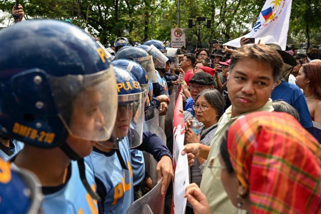 Protesters face police officers as they hold a demonstration to call for the start of the impeachment trial against Philippine Vice-President Sara Duterte and the arrest of Philippine Senator Ronald "Bato" Dela Rosa outside the Senate of the Philippines in Pasay, Metro Manila on May 18, 2026. (Photo by Jam STA ROSA / AFP)