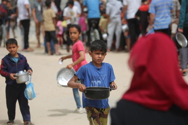 Displaced Palestinian children hold their pot as they wait their turn to collect food from a charity kitchen, in the Bureij refugee camp, in the central Gaza Strip on May 18, 2026. The war has displaced nearly Gaza's entire population and reduced swathes of the Palestinian territory to rubble despite a ceasefire in October 2025, the enclave remains gripped by daily violence as Israeli strikes continue, with both the military and Hamas accusing one another of violating the truce. Hundreds of thousands of people are still living in tents and conditions remain dire despite a ceasefire that took effect in October last year. (Photo by Eyad Baba / AFP)