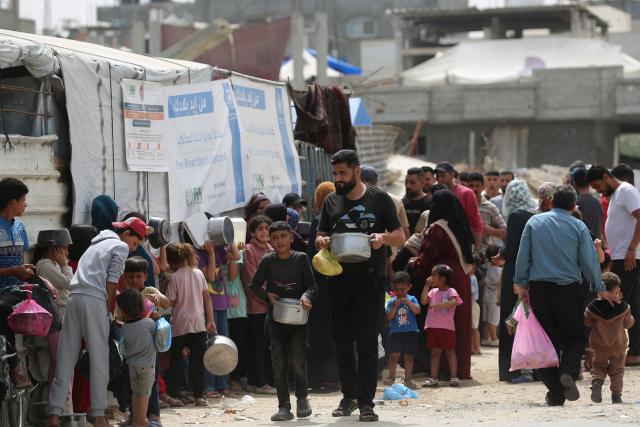 Displaced Palestinian families holding empty containers wait their turn to collect food from a charity kitchen, in the Bureij refugee camp, in the central Gaza Strip on May 18, 2026. The war has displaced nearly Gaza's entire population and reduced swathes of the Palestinian territory to rubble despite a ceasefire in October 2025, the enclave remains gripped by daily violence as Israeli strikes continue, with both the military and Hamas accusing one another of violating the truce. Hundreds of thousands of people are still living in tents and conditions remain dire despite a ceasefire that took effect in October last year. (Photo by Eyad Baba / AFP)
