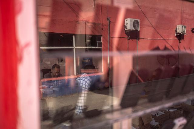 A shop owner sits inside his store at China Town in the Ojota neighbourhood of Lagos on May 5, 2026. (Photo by OLYMPIA DE MAISMONT / AFP)