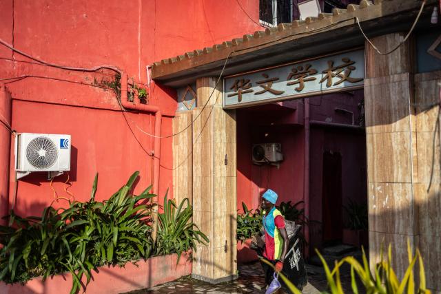 A cleaner carrying waste walks inside China Town in the Ojota neighbourhood of Lagos on May 5, 2026. (Photo by OLYMPIA DE MAISMONT / AFP)