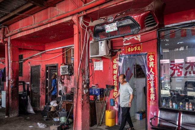 A garage owner walks out of his workshop at China Town in the Ojota neighbourhood of Lagos on May 5, 2026. (Photo by OLYMPIA DE MAISMONT / AFP)