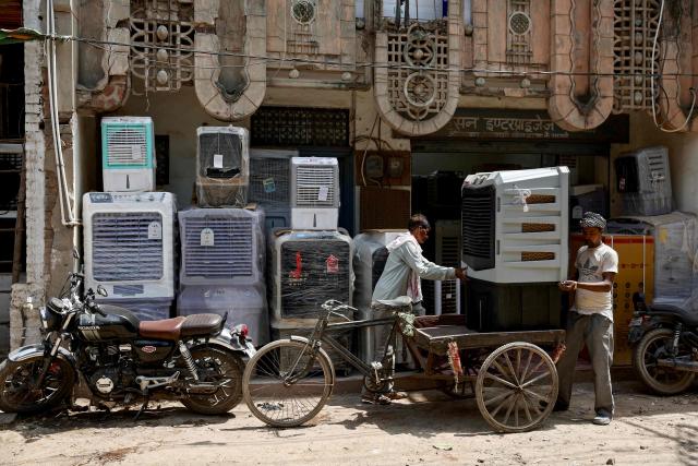 Workers unload a cooler from a cycle cart outside a shop, on a hot summer day in Varanasi on May 18, 2026. (Photo by Niharika KULKARNI / AFP)