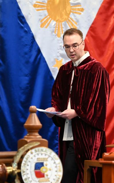 Philippine Senate President and chief judge Alan Cayetano stands next to a Philippine national flag prior to taking his oath in the impeachment trial of Vice President Sara Duterte at the plenary hall of the Senate in Manila on May 18, 2026. Philippine lawmakers were sworn in on May 18 to serve as judges in the trial of impeached Vice President Sara Duterte, the second attempt since last year to force her from office. (Photo by Ted ALJIBE / AFP)