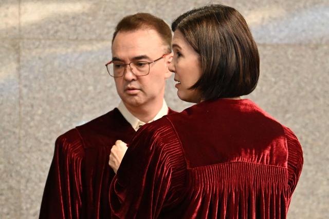 Philippine Senator Pia Cayetano (R), elder sister of Senate President and chief judge Alan Cayetano, fixes the robes of her brother prior to taking their oath as jurors in the impeachment trial of Vice President Sara Duterte at the plenary hall of the Senate in Manila on May 18, 2026. Philippine lawmakers were sworn in on May 18 to serve as judges in the trial of impeached Vice President Sara Duterte, the second attempt since last year to force her from office. (Photo by Ted ALJIBE / AFP)