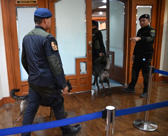 Police officers and their sniffing dogs walk along a hallway after inspecting the plenary hall before the Philippine senators took their oath as jurors in the impeachment trial of Vice President Sara Duterte at the Senate in Manila on May 18, 2026. Philippine lawmakers were sworn in on May 18 to serve as judges in the trial of impeached Vice President Sara Duterte, the second attempt since last year to force her from office. (Photo by Ted ALJIBE / AFP)