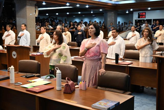 Philippine senators sing the national anthem at the start of regular session prior to taking their oath as jurors in the impeachment trial of Vice President Sara Duterte at the plenary hall of the Senate in Manila on May 18, 2026. Philippine lawmakers were sworn in on May 18 to serve as judges in the trial of impeached Vice President Sara Duterte, the second attempt since last year to force her from office. (Photo by Ted ALJIBE / AFP)