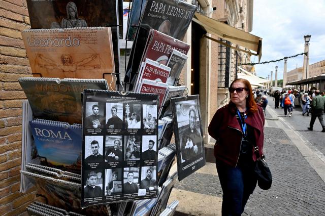 Calendars displaying pictures of models dressed as priests are on sale in souvenirs shops, in Rome on May 18, 2026. (Photo by Andreas SOLARO / AFP)