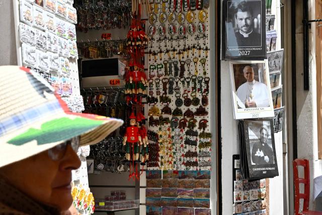 Calendars displaying pictures of models dressed as priests are on sale in souvenirs shops, in Rome on May 18, 2026. (Photo by Andreas SOLARO / AFP)