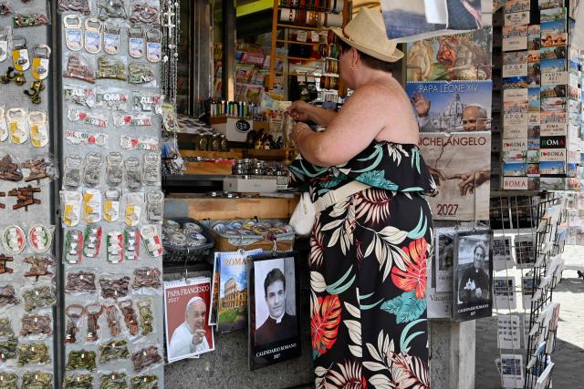 Calendars displaying pictures of models dressed as priests are on sale in souvenirs shops, in Rome on May 18, 2026. (Photo by Andreas SOLARO / AFP)