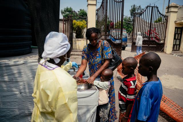 A mother helps her children wash their hands before entering Kyeshero Hospital at a checkpoint for hand washing and temperature screening for all visitors and patients entering Kyeshero Hospital, as part of Ebola prevention measures in Goma on May 18, 2026. A first case of Ebola virus infection has been reported in Goma, a major city in eastern Democratic Republic of Congo controlled by the M23 armed group, with the WHO declaring an international health alert on May 17, 2026. (Photo by Jospin Mwisha / AFP)
