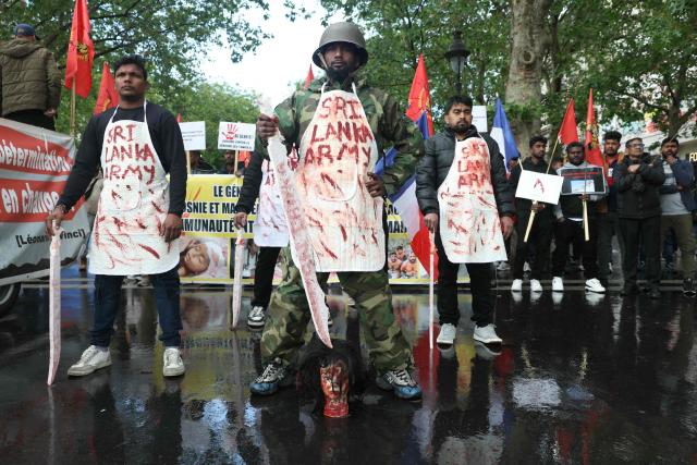 TOPSHOT - Members of the Tamil community in France wearing fake blood-stained aprons bearing the words “Sri Lankan Army” take part in a protest march in Paris on May 18, 2026, demanding that Sri Lanka recognize what they describe as the Tamil genocide. (Photo by Alain JOCARD / AFP)