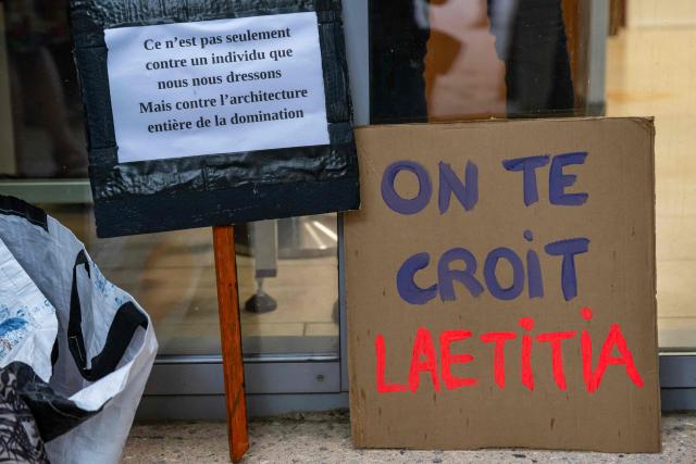 A placard (R) in support of Laetitia R. reads "We believe you Laetitia" is pictured outside the Alpes-de-Haute-Provence court court before the trial of Guillaume B., who is accused of multiple acts of abuse against his partner over seven years from 2015 to 2020, at the  in Digne-les-Bains, southeastern France, on May 18, 2026. The trial of Guillaume B., accused of subjecting his partner to seven years of abuse and rape accompanied by acts of torture, began on May 18, 2026 at the Assize Court in Digne-les-Bains (Alpes-de-Haute-Provence), where he faces a life sentence. (Photo by MIGUEL MEDINA / AFP)