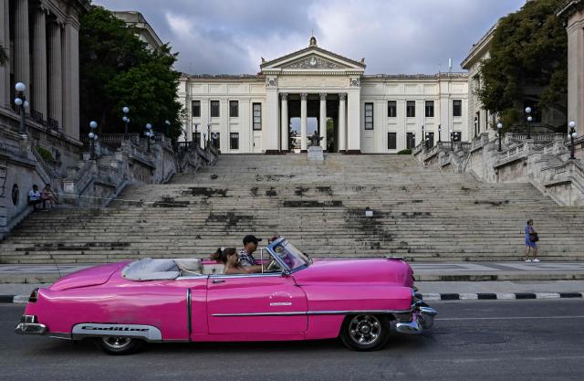 An old car drives past the University of Havana on May 13, 2026. Since February 2026, the fuel crisis in Cuba—marked by the oil blockade imposed by the United States—has left universities without in-person classes. Today, practical degrees such as architecture and design are surviving amid blackouts, shortages and slashed programmes. Training has become so fragmented that an entire generation fears they are being left professionally half-formed. (Photo by YAMIL LAGE / AFP)