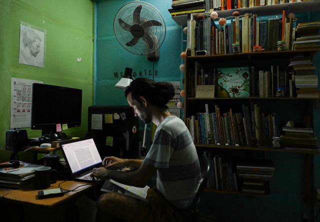 Fourth-year Architecture student Alejandro Benitez studies at home during a power cut in Punta Brava, Havana on May 11, 2026. Since February 2026, the fuel crisis in Cuba—marked by the oil blockade imposed by the United States—has left universities without in-person classes. Today, practical degrees such as architecture and design are surviving amid blackouts, shortages and slashed programmes. Training has become so fragmented that an entire generation fears they are being left professionally half-formed. (Photo by YAMIL LAGE / AFP)