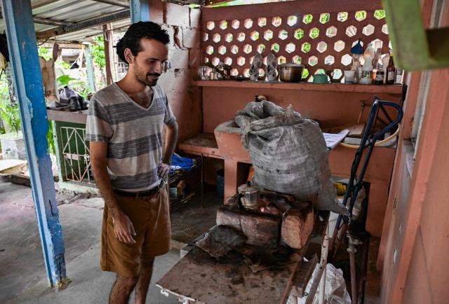 Fourth-year Architecture student Alejandro Benнtez cooks with charcoal during a power cut in Punta Brava, Havana on May 11, 2026. Since February 2026, the fuel crisis in Cuba—marked by the oil blockade imposed by the United States—has left universities without in-person classes. Today, practical degrees such as architecture and design are surviving amid blackouts, shortages and slashed programmes. Training has become so fragmented that an entire generation fears they are being left professionally half-formed. (Photo by YAMIL LAGE / AFP)