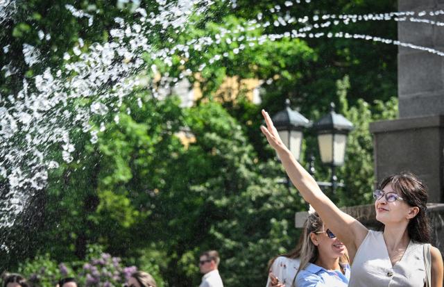 A woman tries to refresh herself in a fountain in downtown Moscow on May 18, 2026, as the temperature raised up to 30 centigrade. (Photo by Alexander NEMENOV / AFP)