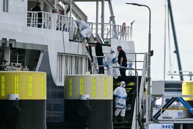 Crew members help persons in protective hazmat suits carrying resealable pouches and vials to disembark from the Dutch Hantavirus-hit cruise ship MV Hondius docked at the port of Rotterdam on May 18, 2026. A cruise ship that sparked global alarm after a deadly outbreak of hantavirus docked in Rotterdam harbour on May 18, with the skeleton crew facing weeks of quarantine. (Photo by NICOLAS TUCAT / AFP)