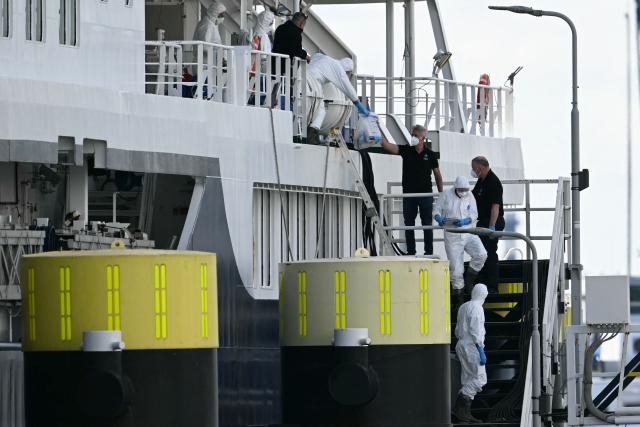 Crew members help persons in protective hazmat suits carrying resealable pouches and vials to disembark from the Dutch Hantavirus-hit cruise ship MV Hondius docked at the port of Rotterdam on May 18, 2026. A cruise ship that sparked global alarm after a deadly outbreak of hantavirus docked in Rotterdam harbour on May 18, with the skeleton crew facing weeks of quarantine. (Photo by NICOLAS TUCAT / AFP)