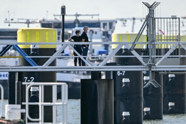 Two crew members await to leave the Dutch Hantavirus-hit cruise ship MV Hondius docked at the port of Rotterdam on May 18, 2026. A cruise ship that sparked global alarm after a deadly outbreak of hantavirus docked in Rotterdam harbour on May 18, with the skeleton crew facing weeks of quarantine. (Photo by NICOLAS TUCAT / AFP)