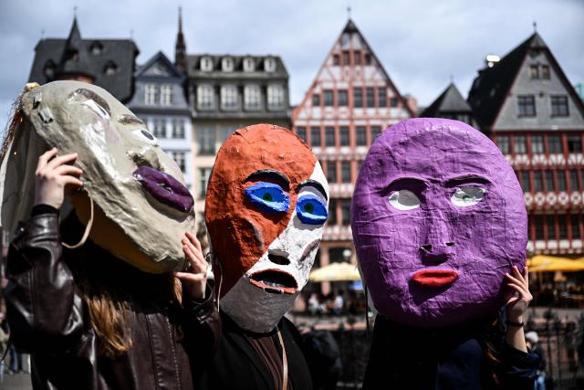 Participants wearing masks gestures during a rally in support of student theatres on the central Roemer Square in Frankfurt am Main, western Germany, on May 18, 2026. (Photo by Kirill KUDRYAVTSEV / AFP)