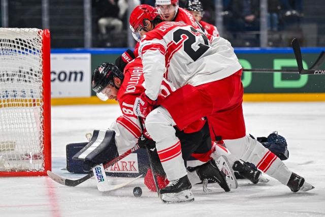 Canada’s forward #81 Dylan Holloway (L) and Denmark's defender #22 Markus Lauridsen fight for the puck during the groupe B match between Canada and Denmark at the IIHF Ice Hockey Men's World Championship at BFC Arena, in Fribourg, Switzerland, on May 18, 2026. (Photo by Fabrice COFFRINI / AFP)