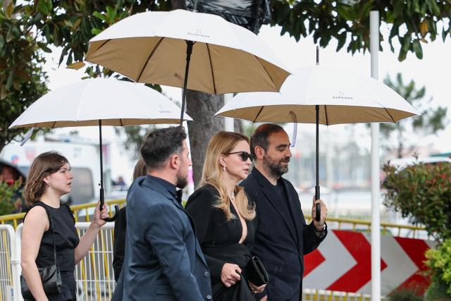 Belgian-French actress Virginie Efira (C) and Iranian co-Producer Ardavan Safaee (C-R) walk under umbrellas on the Boulevard de la Croisette on the sidelines of the 79th edition of the Cannes Film Festival in Cannes, southern France, on May 18, 2026. (Photo by SAMEER AL-DOUMY / AFP)