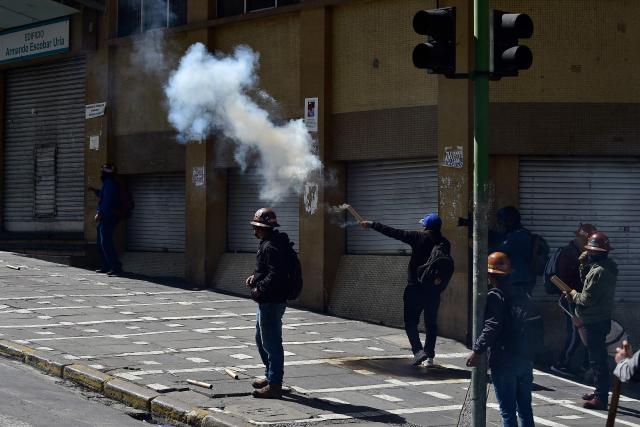 Miners clash with riot police during a protest demanding the resignation of Bolivian President Rodrigo Paz, in La Paz, on May 18, 2026. Bolivians have taken to the streets for the past two weeks, blocking roads into La Paz and disrupting deliveries of food, medicine and other goods to the seat of government, while demanding higher wages, economic relief and the resignation of centre-right President Rodrigo Paz amid a severe economic crisis. (Photo by Jorge BERNAL / AFP)