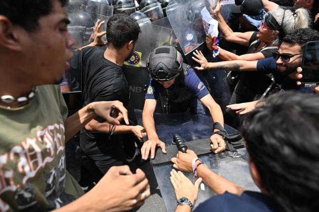 Students of the Central University of Venezuela (UCV) scuffle with Bolivarian National Police (PNB) officers during a protest following the death of Carmen Navas, the mother of late political prisoner Victor Quero Navas, in Caracas, on May 18, 2026. The mother of political prisoner Victor Quero died on May 17 at the age of 81, just days after confirming that her son had died nine months earlier while in the custody of the Venezuelan state, relatives told AFP. (Photo by Juan BARRETO / AFP)
