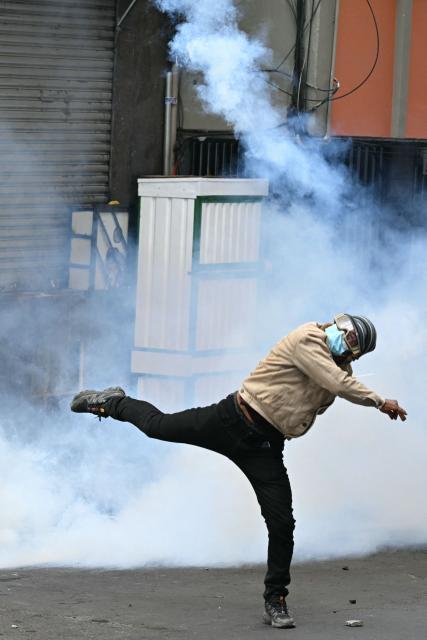 A miner throws a tear gas canister back at riot police during a protest demanding the resignation of Bolivian President Rodrigo Paz, in La Paz, on May 18, 2026. Bolivians have taken to the streets for the past two weeks, blocking roads into La Paz and disrupting deliveries of food, medicine and other goods to the seat of government, while demanding higher wages, economic relief and the resignation of centre-right President Rodrigo Paz amid a severe economic crisis. (Photo by AIZAR RALDES / AFP)