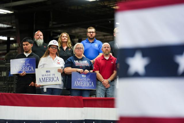 Employees of the Milbank Manufacturing Company hold signs as US Senator Eric Schmitt, Republican of Missouri speaks during an event with US Vice President JD Vance at Milbank Manufacturing Company in Kansas City, Missouri, on May 18, 2026. (Photo by Eric Lee / POOL / AFP)